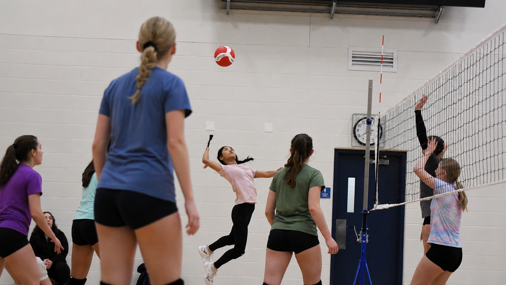Girls playing volleyball near the net in an indoor gym